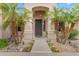 Home's entrance features a decorative iron door, stone walkway, and desert landscaping with palm trees at 6870 S Justin Way, Chandler, AZ 85249