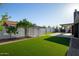 Lush backyard featuring artificial turf, white block fence, trees, and a covered patio at 7425 W Corrine Dr, Peoria, AZ 85381