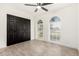 Bright bedroom with wood-look tile flooring, ceiling fan, windows, and closet with black paneled doors at 7425 W Corrine Dr, Peoria, AZ 85381