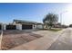 Single-story home with a well-maintained driveway, a black garage door, and a red front door at 7425 W Corrine Dr, Peoria, AZ 85381