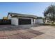 Single-story home with a well-maintained driveway, a black garage door, and a red front door at 7425 W Corrine Dr, Peoria, AZ 85381
