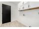 Clean laundry room featuring tiled floors, overhead cabinetry, and black doors at 7425 W Corrine Dr, Peoria, AZ 85381