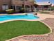 Manicured backyard showcasing pool, synthetic grass, and a view of the patio and back of the home at 8732 W Adam Ave, Peoria, AZ 85382