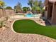 Fully fenced backyard with synthetic grass, rock landscaping, swimming pool, and outdoor entertaining areas at 8732 W Adam Ave, Peoria, AZ 85382