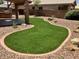 View of landscaped backyard featuring artificial grass, concrete edging, and gravel landscaping at 8732 W Adam Ave, Peoria, AZ 85382