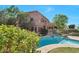 A luxurious home exterior featuring a swimming pool, balcony, and lush landscaping at 8732 W Adam Ave, Peoria, AZ 85382