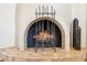 Close-up view of a cozy fireplace with decorative ironwork and a tile hearth at 9460 N 105Th Pl, Scottsdale, AZ 85258