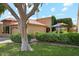 View of the front exterior of the single story home, green lush yard and mature tree shading the lawn at 9460 N 105Th Pl, Scottsdale, AZ 85258