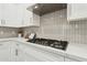 Close-up of a modern gas range and hood with white countertops and cabinets at 1 Easy St # 4, Carefree, AZ 85377