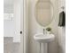 Bright powder room featuring a pedestal sink, oval mirror, and gray hand towel near a white door at 1 Easy St # 4, Carefree, AZ 85377
