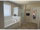 Bright bathroom featuring a soaking tub, glass-enclosed shower, and neutral tile flooring at 11121 E Sombra Ave, Mesa, AZ 85212