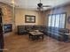Comfortable living room featuring a stone fireplace, ceiling fan, and a large leather sofa at 12937 W Calle De Sol --, Peoria, AZ 85383
