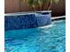 Serene pool with a vibrant blue tile waterfall feature, perfect for relaxation and adding a touch of luxury to outdoor living at 12937 W Calle De Sol --, Peoria, AZ 85383
