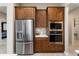 Close up of stainless steel refrigerator, microwave, and ovens with wood cabinetry and tile backsplash at 16953 W Merrell St, Goodyear, AZ 85395