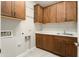 Well-lit laundry room with wood cabinets, sink, and tile floors at 16953 W Merrell St, Goodyear, AZ 85395