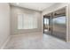 Bright, minimalist living area with tile flooring, large window, and sliding glass door access at 16953 W Merrell St, Goodyear, AZ 85395