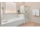 Bright bathroom features a soaking tub, a separate glass enclosed shower, and a window providing natural light at 17773 W Manso St, Goodyear, AZ 85338
