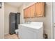 Functional laundry room with wooden cabinets, grey storage cabinet, and modern washer and dryer at 17773 W Manso St, Goodyear, AZ 85338