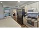 Bright kitchen with stainless steel appliances, white cabinets, and a view into a room with a piano at 1904 E Jarvis Ave, Mesa, AZ 85204