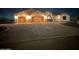 Night view of a home's illuminated façade with a two-car garage, showcasing its curb appeal at 19880 W Desert Views Dr, Casa Grande, AZ 85122