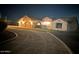 Night view of a home's illuminated façade with a two-car garage, showcasing its curb appeal at 19880 W Desert Views Dr, Casa Grande, AZ 85122