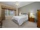 Cozy primary bedroom featuring a ceiling fan, plush carpet, and a large window with stylish floral valances at 20039 N Hearthstone Dr, Surprise, AZ 85374