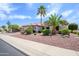 Desert landscaping surrounds this single-story home with a tiled roof and palm trees at 20039 N Hearthstone Dr, Surprise, AZ 85374