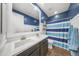 Bathroom with a dual sink vanity, blue walls, white shiplap, and a shower with blue accents at 20458 W Briarwood Dr, Buckeye, AZ 85396