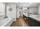Bright bathroom with wood floors, white vanities with double sinks, soaking tub, and glass shower at 20458 W Briarwood Dr, Buckeye, AZ 85396