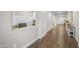 Bright hallway with wood floors, white walls, and view of office nook featuring modern chair and desk at 20458 W Briarwood Dr, Buckeye, AZ 85396
