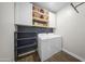 Bright laundry room features white cabinets, floating shelves, and modern washer and dryer at 20458 W Briarwood Dr, Buckeye, AZ 85396