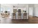 An open kitchen features an island with barstool seating, wooden floors, and white cabinetry at 25720 W White Feather Ln, Wittmann, AZ 85361
