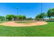 Well-maintained baseball field with green grass and tall lights surrounded by trees at 25995 W Sierra Pinta Dr, Buckeye, AZ 85396