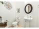 Cozy powder room featuring pedestal sink, round mirror, and decorative wall art at 25995 W Sierra Pinta Dr, Buckeye, AZ 85396
