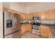 This well-maintained kitchen includes wooden cabinets, tile flooring, and stainless steel appliances at 2922 N 107Th Dr, Avondale, AZ 85392