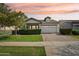 Charming home featuring a well-manicured front yard, brick driveway, and neutral-colored facade set against a sunset sky at 3163 E Austin Dr, Gilbert, AZ 85296