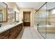 Elegant bathroom with dual sinks, wooden cabinets, a soaking tub, and a walk-in glass shower at 35971 N Prickley Pear Rd, Cave Creek, AZ 85331