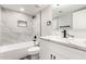 Renovated bathroom with a marble tiled shower, white vanity, and black hardware at 3752 W Becker Ln, Phoenix, AZ 85029