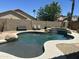 Backyard pool with rock features, an attached spa, and a desert landscape with a privacy wall at 7326 W Dreyfus Dr, Peoria, AZ 85381