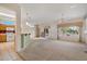 Bright living room with large windows, carpeting, and an open layout leading to the kitchen at 15313 W Pantano Dr, Surprise, AZ 85374