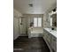 A bathroom with a shower, bathtub, vanity and a window bringing natural light to the hardwood flooring at 15742 W Central St, Surprise, AZ 85374
