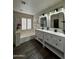 Bathroom featuring double vanity sinks, a bathtub, a shower, hardwood floors, and a window at 15742 W Central St, Surprise, AZ 85374