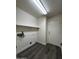 A laundry room includes wood-look flooring, a white door, and shelving for storage at 15742 W Central St, Surprise, AZ 85374