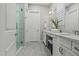 Bright bathroom featuring double sinks, quartz counters, gray tile flooring, and glass-enclosed shower at 17376 W Wildwood St, Surprise, AZ 85388