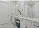 Bright bathroom featuring double sinks, quartz counters, gray tile flooring, and glass-enclosed shower at 17376 W Wildwood St, Surprise, AZ 85388
