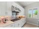 Bright kitchen with white cabinetry, stainless hood, gas range, and stone countertops at 17376 W Wildwood St, Surprise, AZ 85388