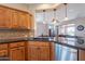 An island sink with wood cabinets and stainless steel appliances complements the open kitchen design at 1809 E Adelante Way, Queen Creek, AZ 85140