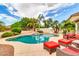 A serene pool with rock waterfall feature, mature palm trees, and comfortable seating areas, perfect for relaxation and leisure at 20423 S 186Th St, Queen Creek, AZ 85142