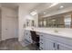 Bright bathroom featuring double sinks, a vanity area, and a tiled shower in a well-lit space at 22184 N 101St Dr, Peoria, AZ 85383