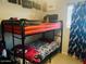 A bedroom featuring a bunk bed with black frames, a red top bunk, and a black-and-white patterned bottom bunk at 2377 W Hazelwood St, Phoenix, AZ 85015